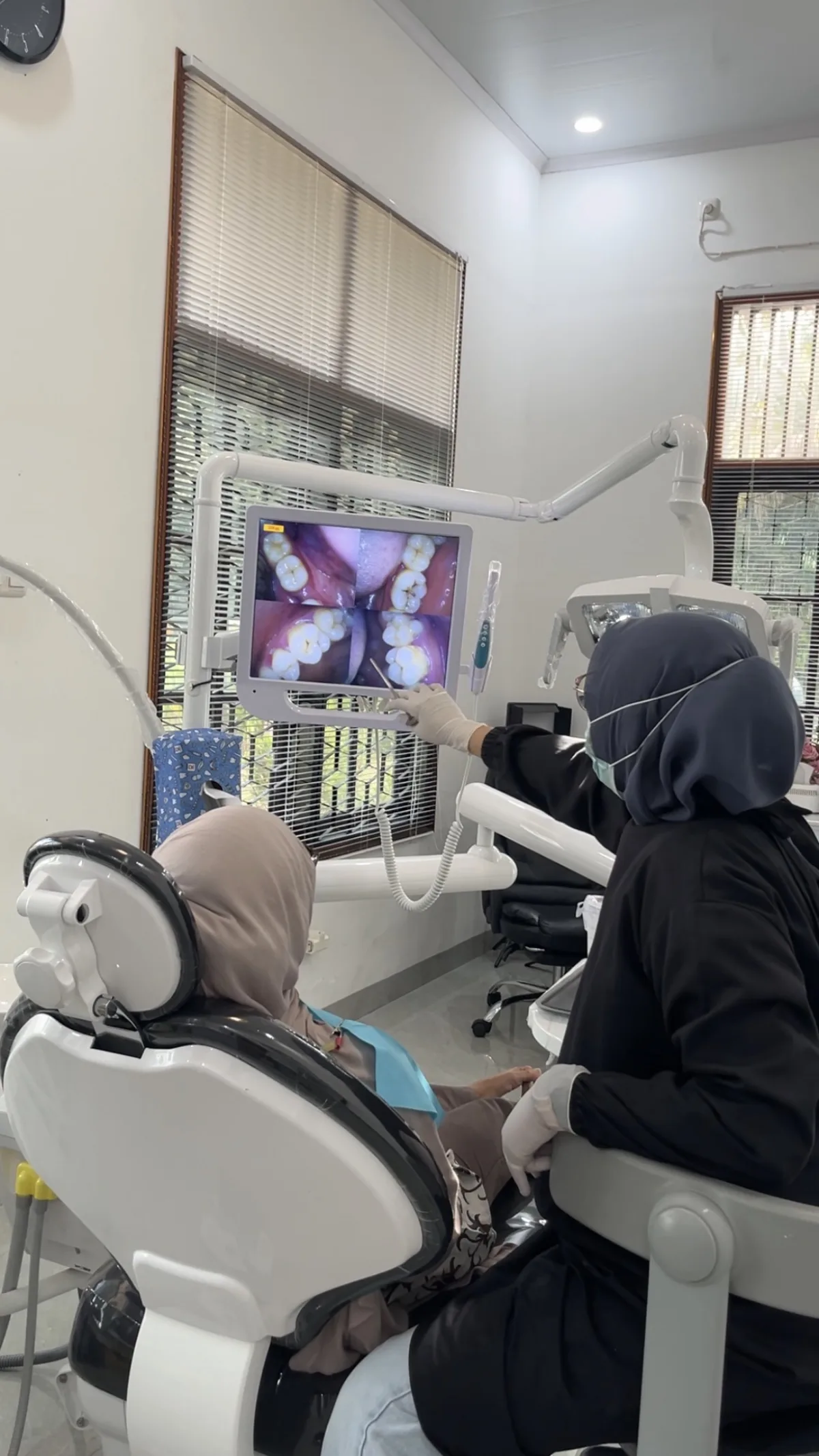 Dokter DOP Dental menjelaskan kondisi gigi pasien melalui layar pemeriksaan